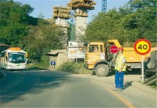 Imagen de apoyo para la pregunta: En este tramo en obras, ¿debe obedecer la señal de STOP que sujeta el operario para facilitar la incorporación del camión que sale desde un camino de tierra?
